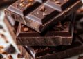 dark chocolate bars stacked on marble with cocoa nibs