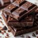 dark chocolate bars stacked on marble with cocoa nibs